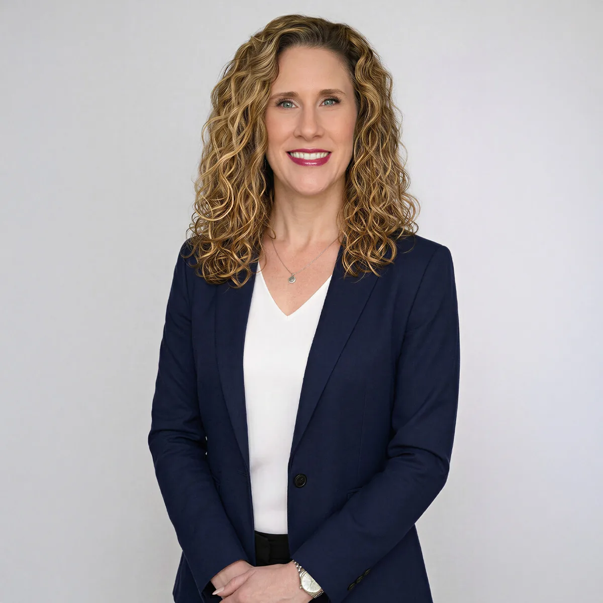 Professional portrait of a woman in a navy blazer against a light gray backdrop