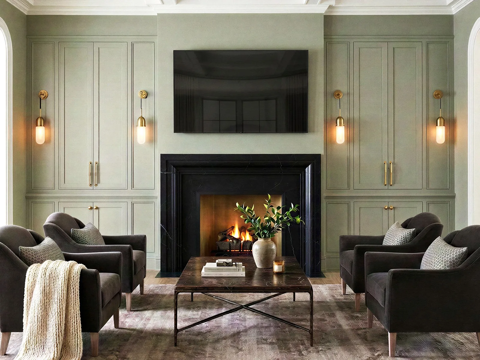 Rendered family room fireplace wall: sage built-ins, brass sconces, black marble surround and four armchairs